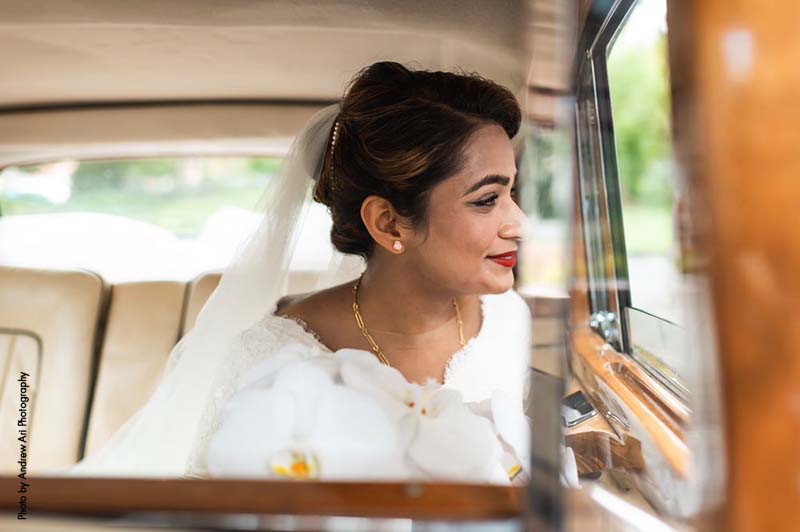 Bride with classic makeup and updo sits in vintage car