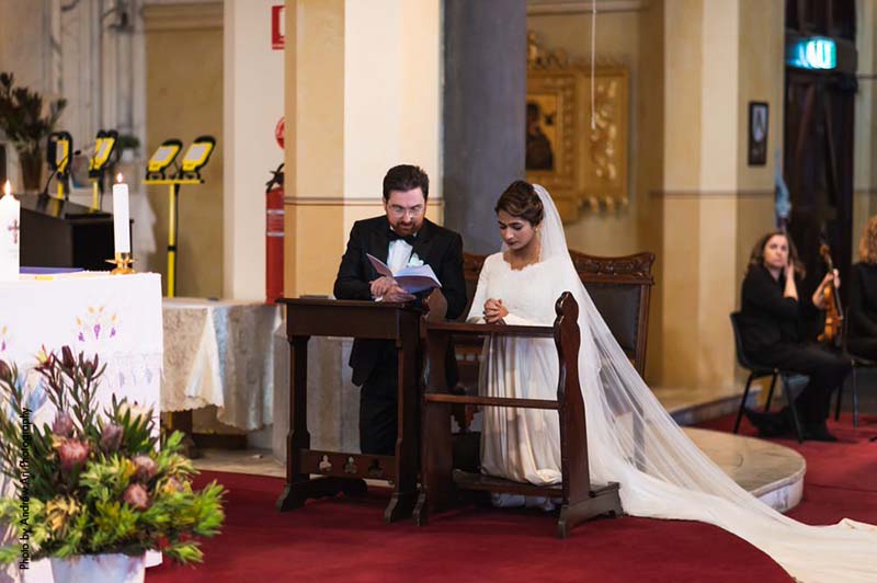 Bride and groom kneel during traditional Catholic wedding