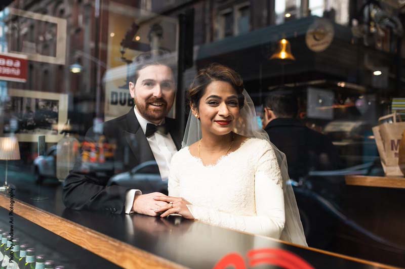 Bride and groom sit inside of a bistro