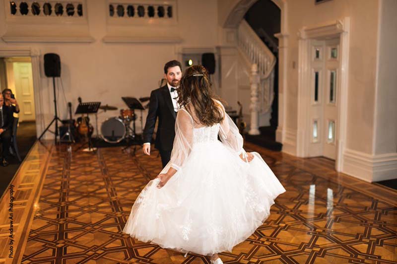 Bride in tea-length dress and groom in black tux share first dance