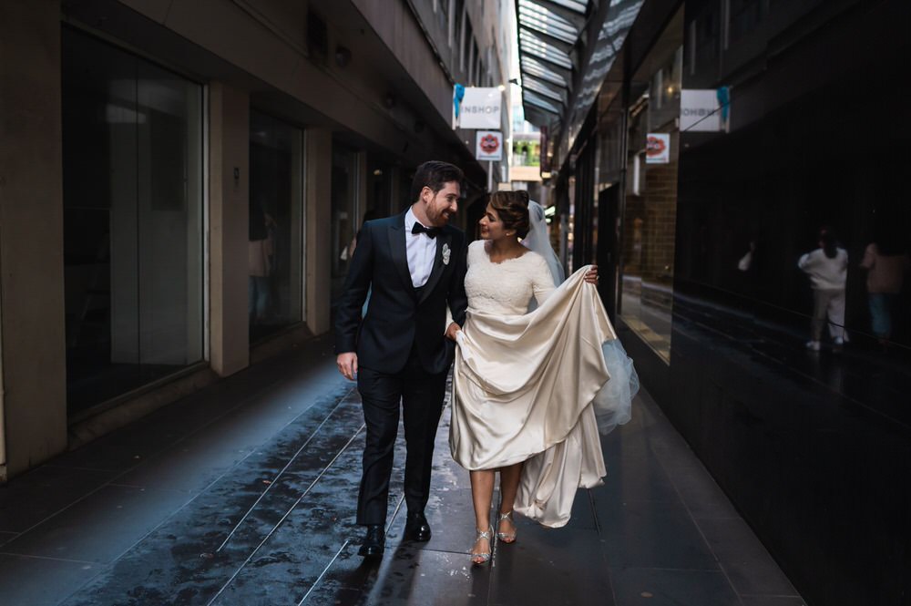 Bride and groom walk down alley after Italian-style wedding