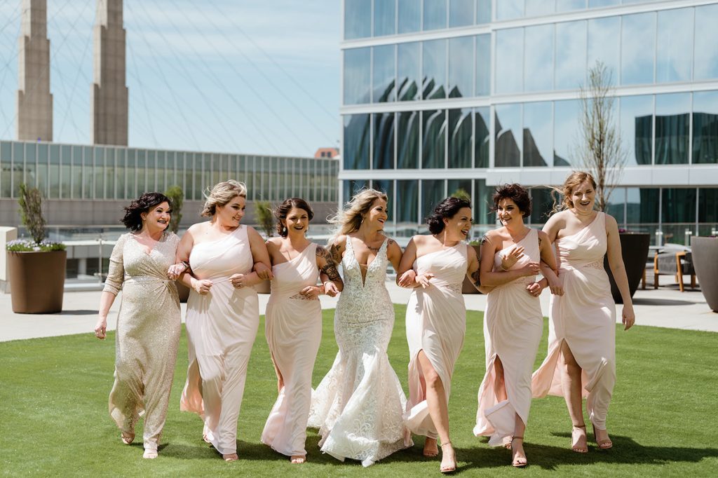Bridesmaids in light pink dresses walk with bride 