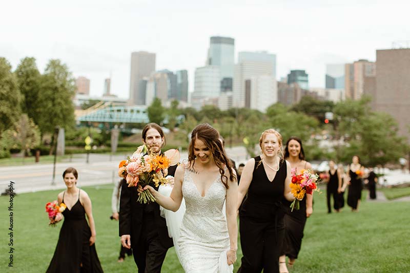 Bride walking in grass with her wedding party