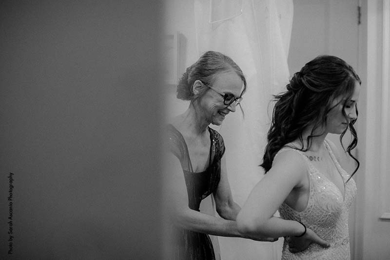 Mother helps bride with gown