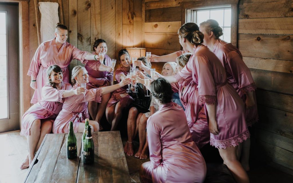 Bridal party in pink robes cheers with champagne