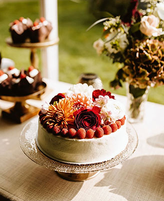 Single-tier white wedding cake with fall flowers on top