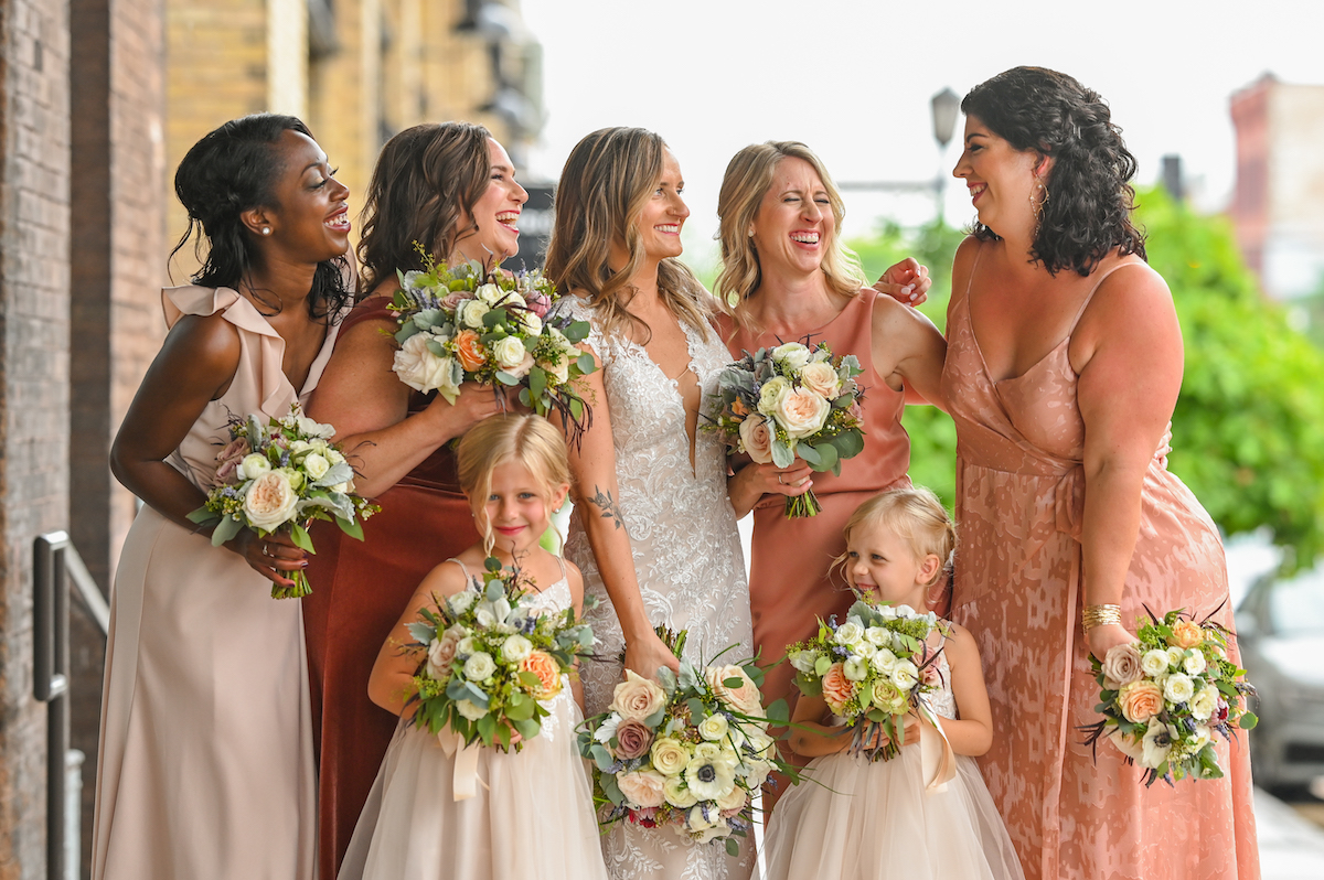 Bridesmaids in mismatched blush and orange gowns