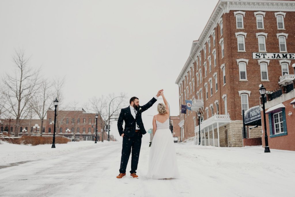 Couple twirls in the snow outside of the St. James Hotel in Minnesota