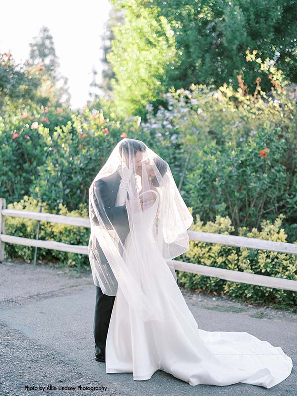 Bride and groom kiss under bridal veil
