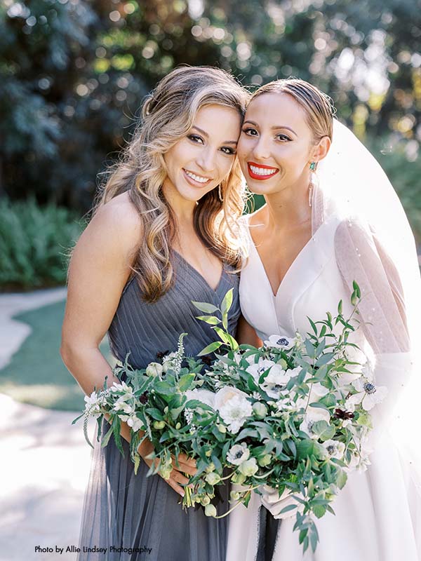 Bride with cathedral veil poses with her bridesmaid