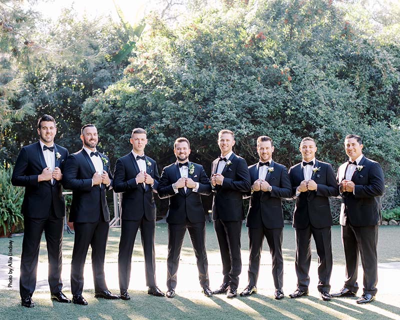 Groomsmen in black tuxes stand side by side