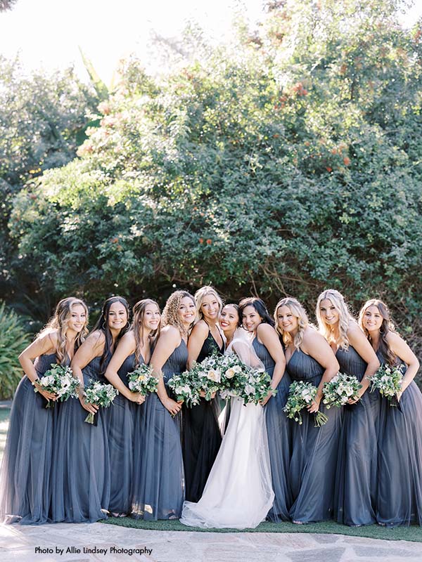 Brides stands with bridesmaids in gray dresses