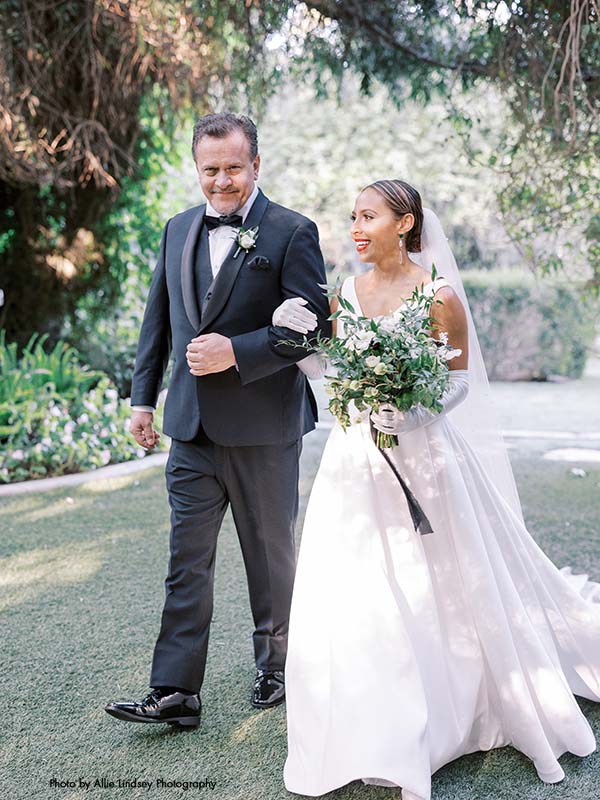 Bride in a-line satin gown walks down the aisle with her father