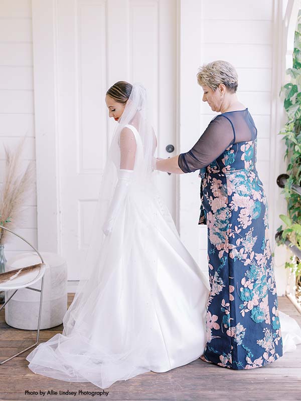 Mother of the bride helps bride put on her dress