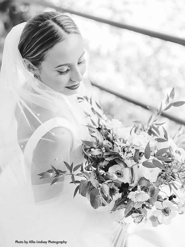 Bride looks at her modern wedding bouquet with anemone and greenery