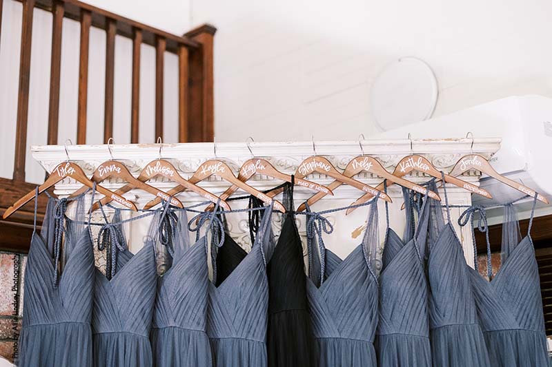 Gray and black bridesmaid dresses hang on wooden hangers