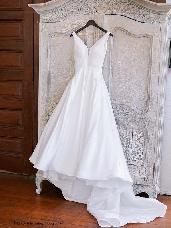 A-line v-neck satin wedding dress sits on a hanger