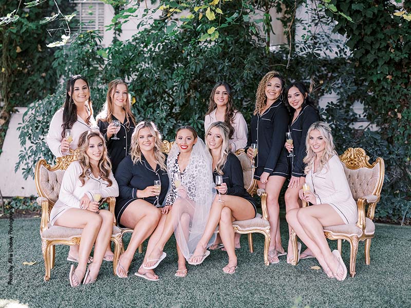Wedding party in black and blush robes sit with bride in leopard robe