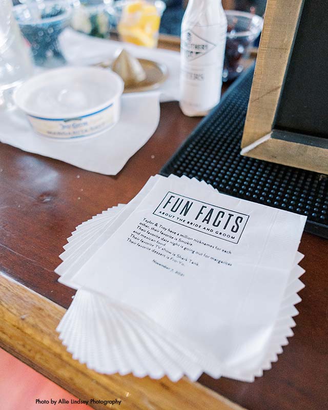 White cocktail napkins with fun facts about the bride and groom printed on them