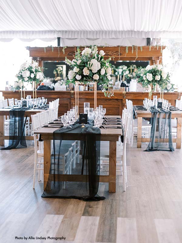 Wedding head table with black runner and tall white and greenery centerpieces