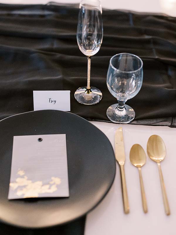 White and gold foil menu sits atop a matte black black