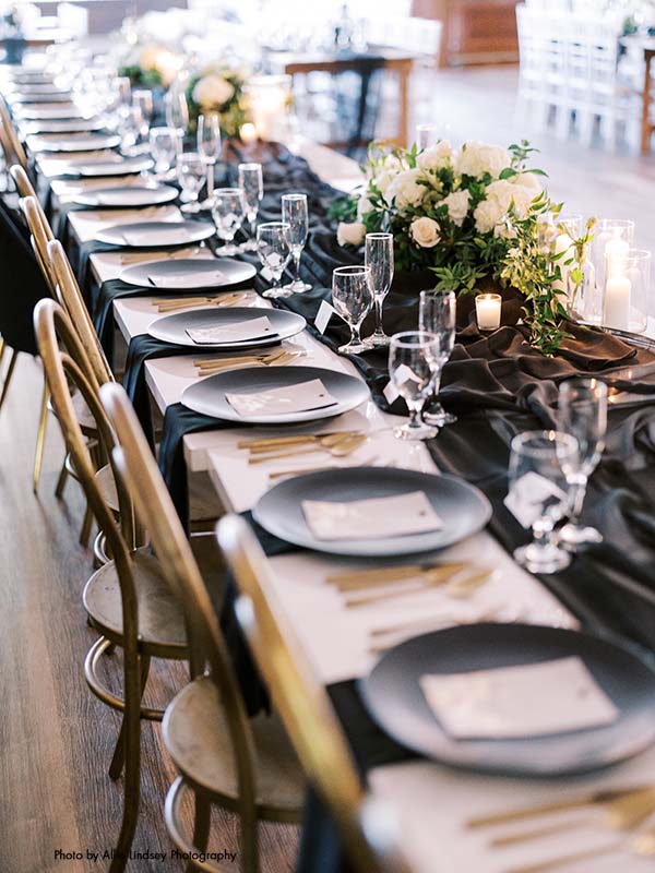 Wedding table with satin black runner and matte black plates with gold flatware