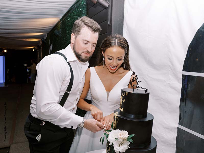 Bride and groom cut 3-tier black wedding cake