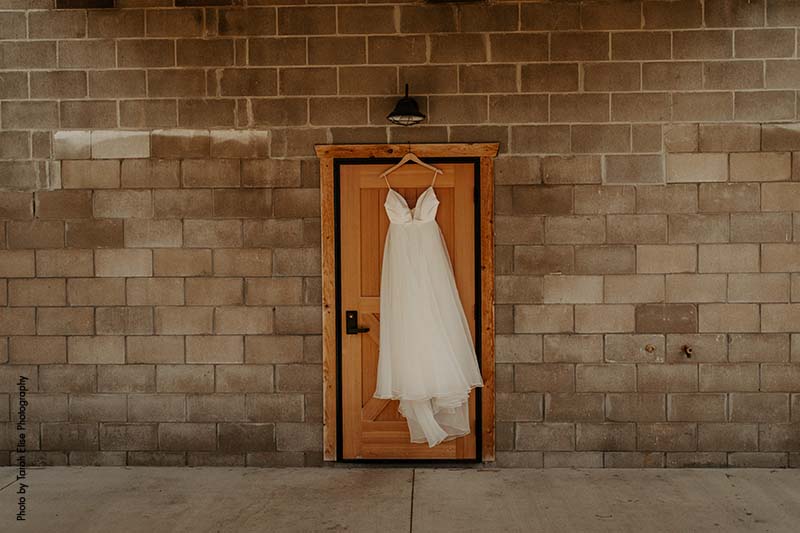 A-line bridal gown hangs from wooden door