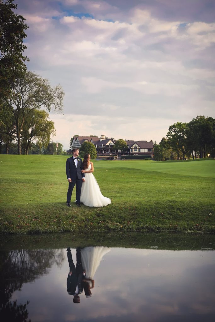 Bride and groom stand on golf course greens