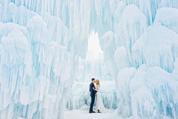 Bride and groom post under ice castle in Minnesota