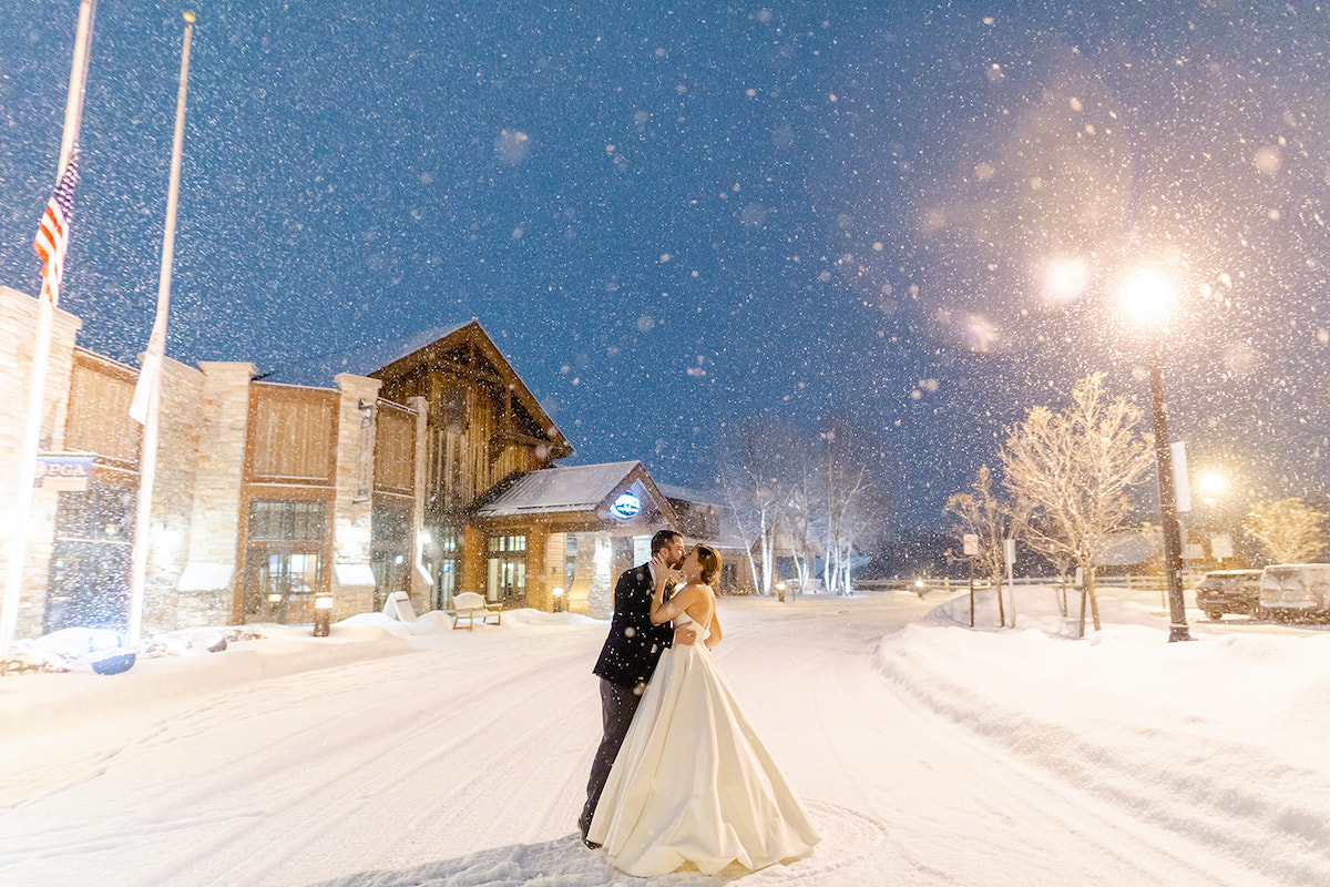 Bride and groom stand outside wedding venue as it snows 