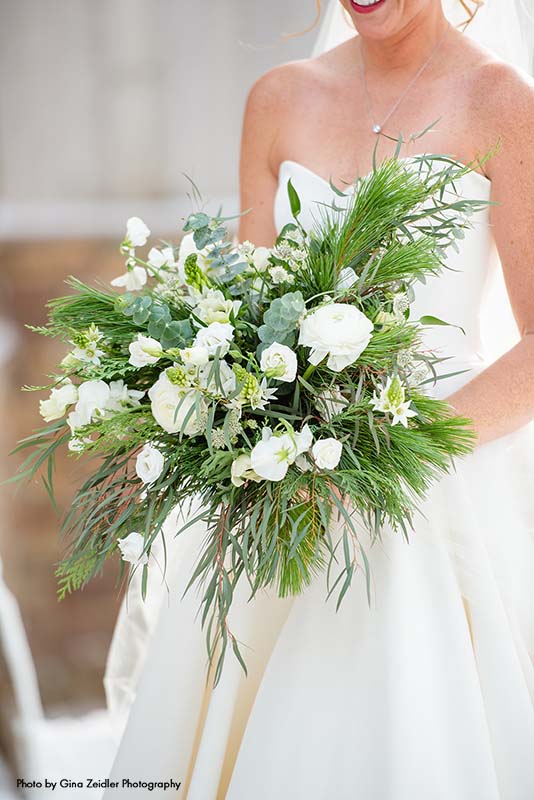 Bride holds winter bouquet with plush greenery and pine