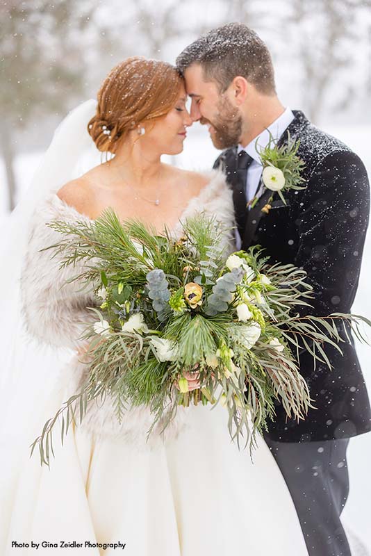 Bride and groom stand outside as it snows