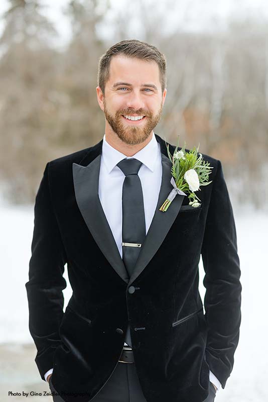 Groom in velvet suit jacket and greenery boutonniere