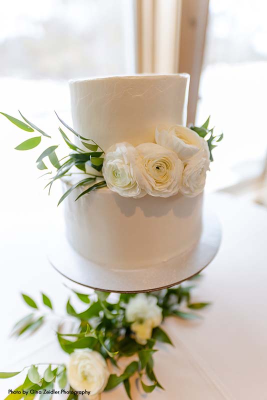2-tier white wedding cake with white ranunculus