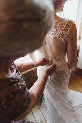 Mother of the bride helps bride zip up gown