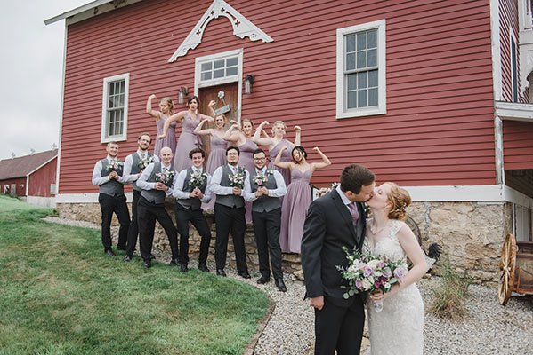 Wedding party poses outside barn