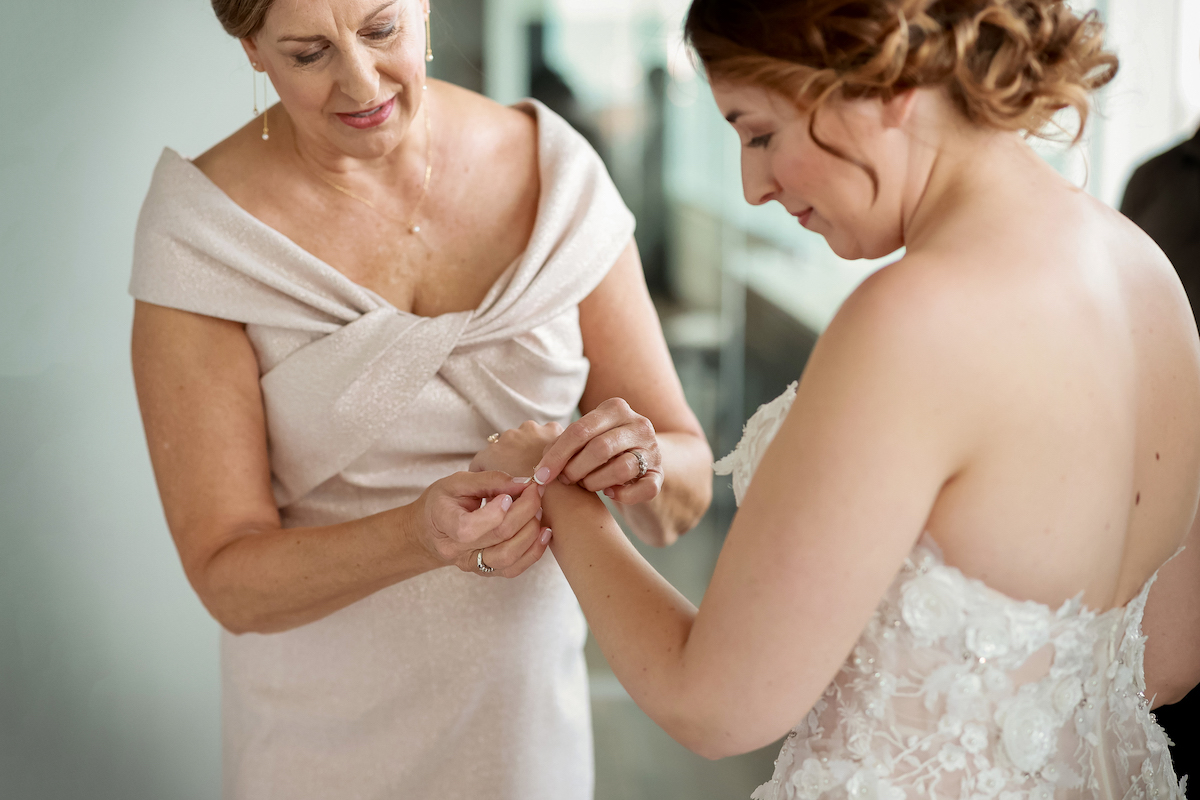 Mother of the bride places bracelet on bride's wrist