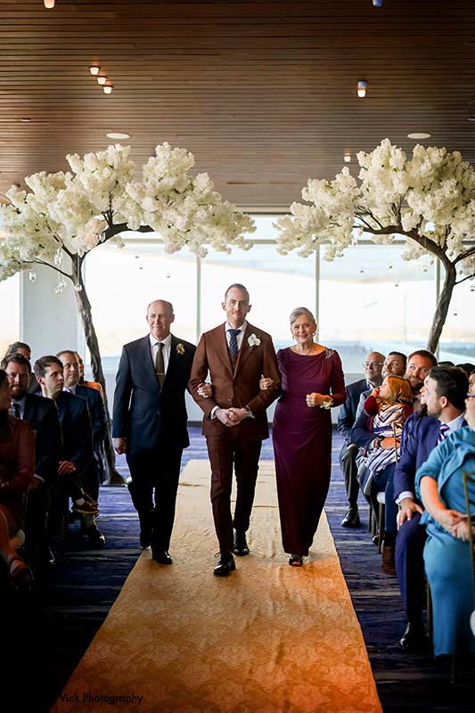 Grooms walks down the aisle with parents
