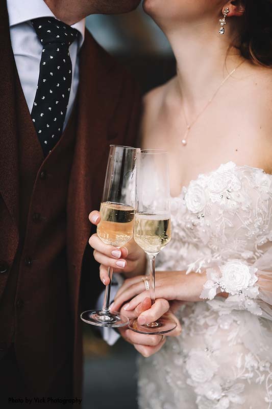 Bride and groom hold champagne glasses