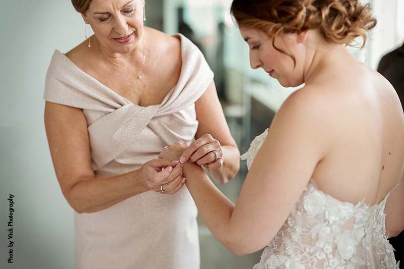 Mother of the bride helps place bracelet on bride