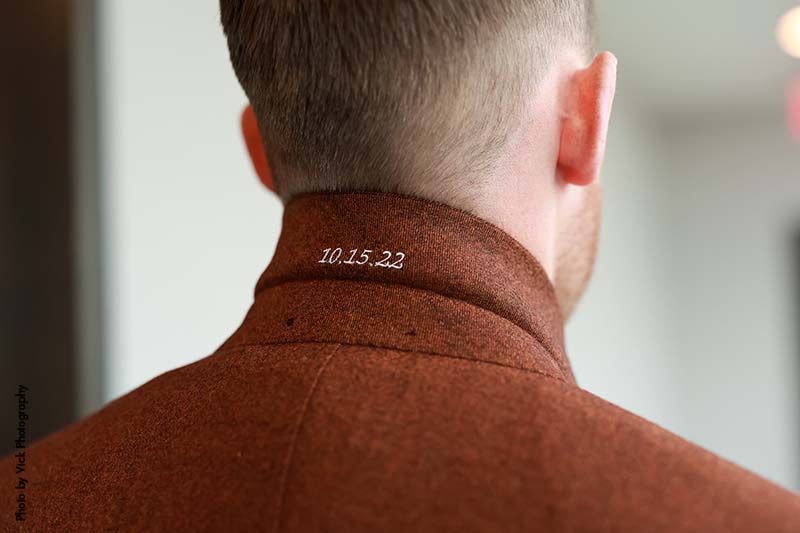 Custom stitching in groom's suit that says "10-15-22"