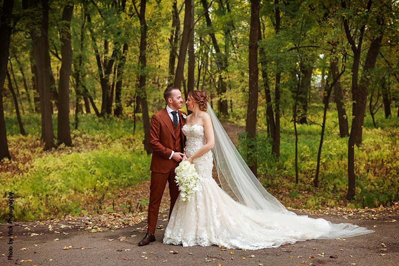 Bride and groom stand outside in fall foliage