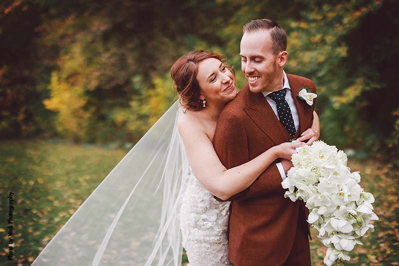 Bride and groom pose with fall foliage