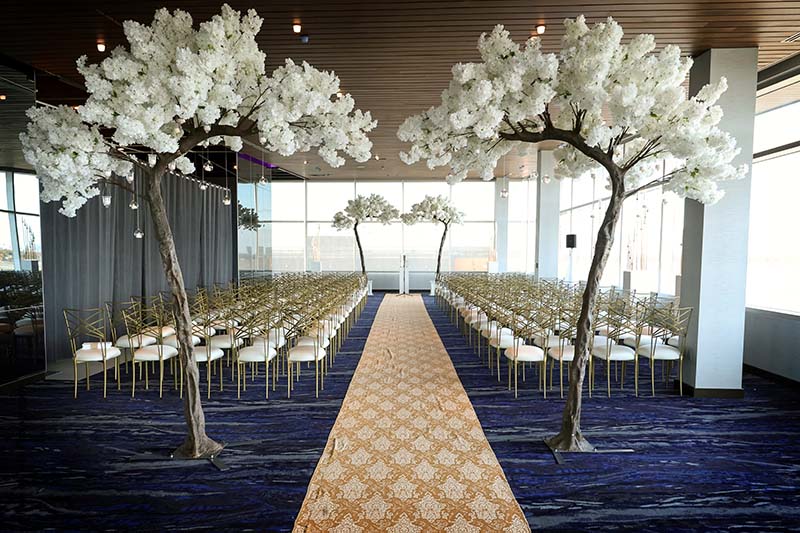 Wedding ceremony with flowering trees and deep yellow damask aisle runner
