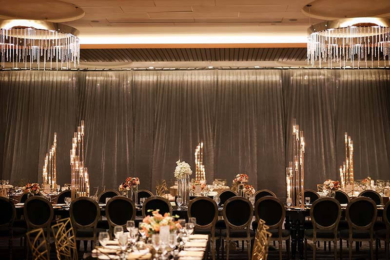 Wedding reception with black chairs and gold candlabras