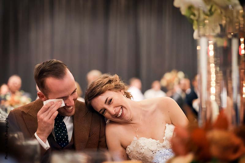 Bride and groom laugh during wedding speeches