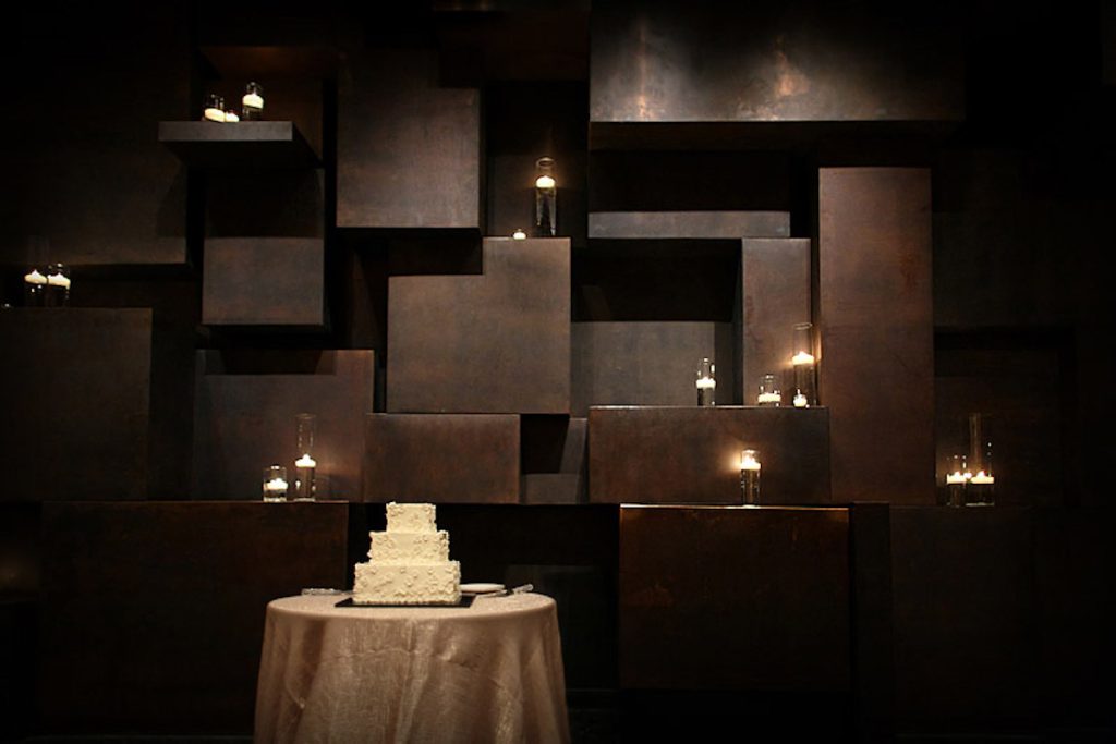 3-tiered white wedding cake sits in front of black wall